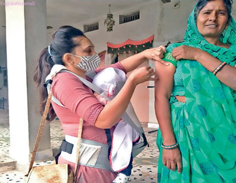  છ માસની બાળકીને ઝોળીમાં રાખી નાગરિકોને રસી આપતી હેલ્થ વર્કર